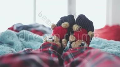 在一个模糊的背景下，穿着袜子和可爱的泰迪熊，穿着睡衣，在床上徒步玩耍